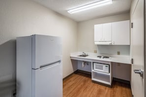 Una cocina compacta equipada con refrigerador, microondas y pileta.
