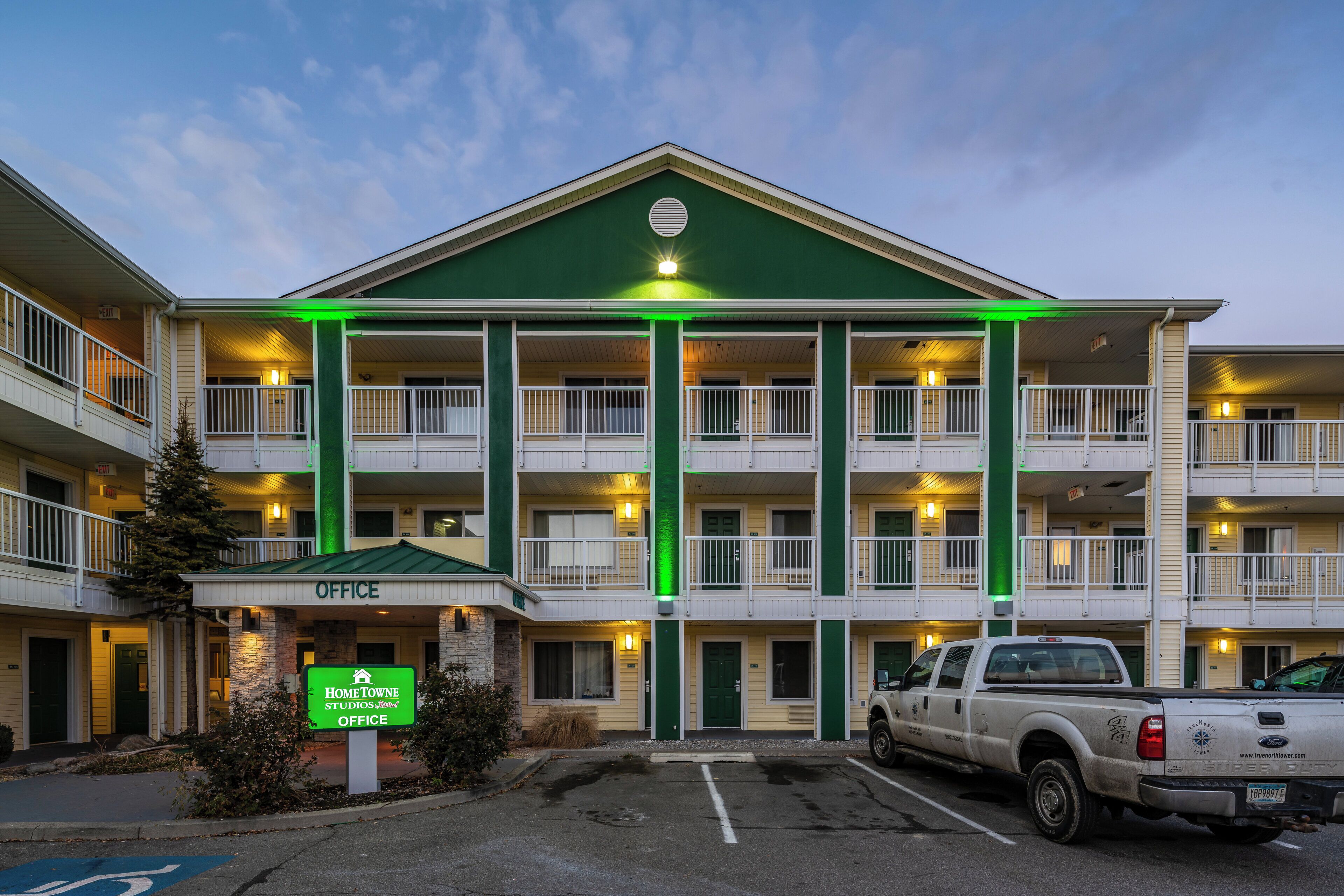 A multi-story motel with a green entrance and a sign for the Home Towne Studios office.