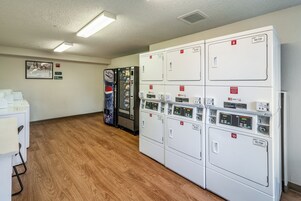 A row of self-service vending machines and a row of dryers in a hotel room.