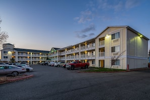 A multi-story motel with a parking lot. - HomeTowne Studios by Red Roof Spokane - Valley (Spokane Valley)