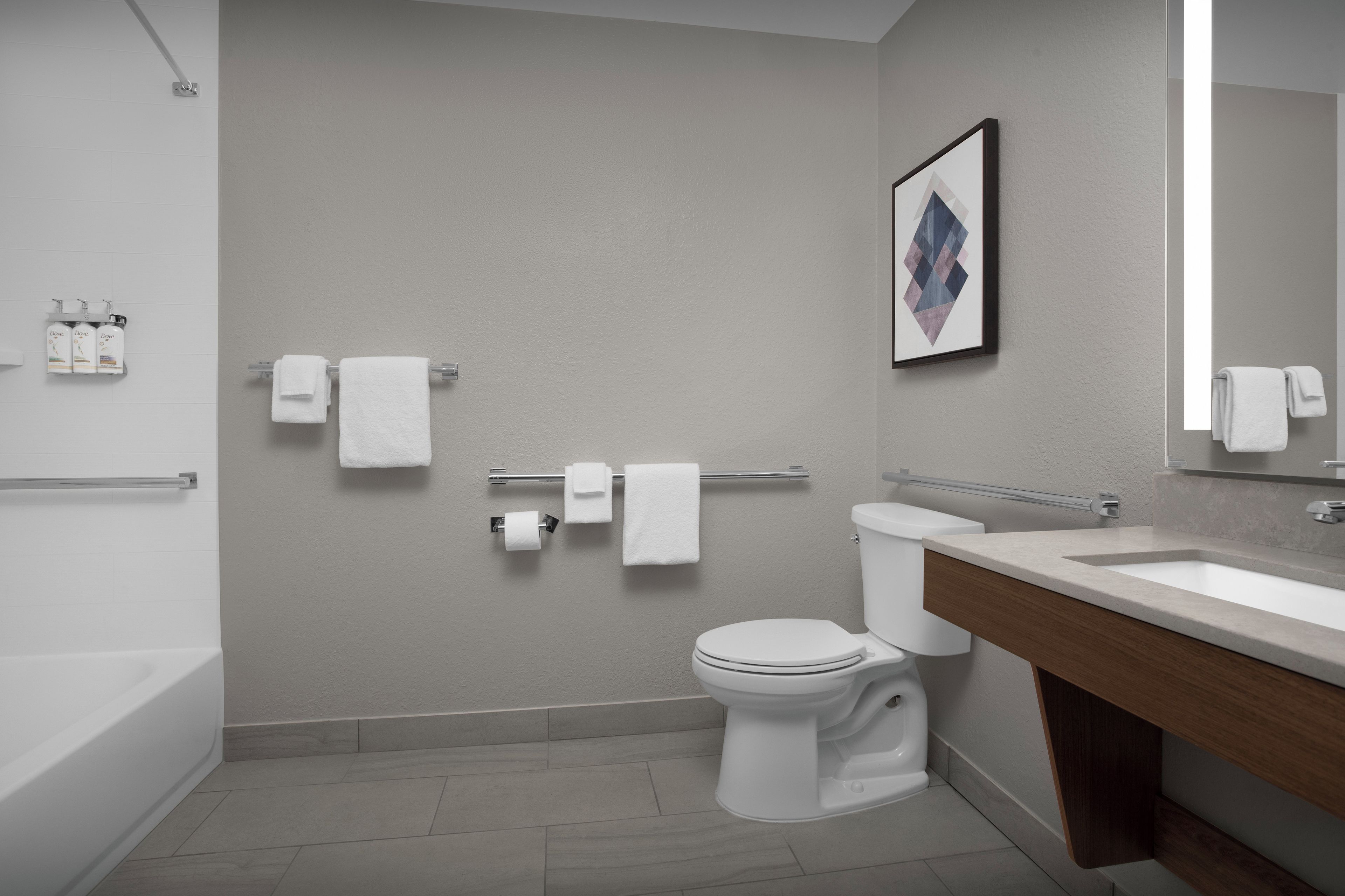A modern bathroom with a bathtub, toilet, and vanity.