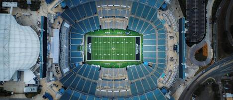 An aerial view of a stadium with a football field, seating areas, and surrounding roads.