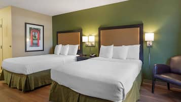 A hotel room with two beds, a framed picture on the wall, and a chair.