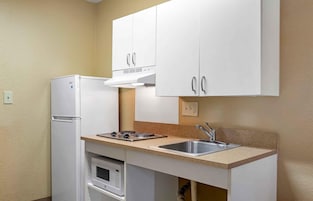 Una cocina compacta con armarios blancos, horno empotrado, cocina a gas y un lavamanos.
