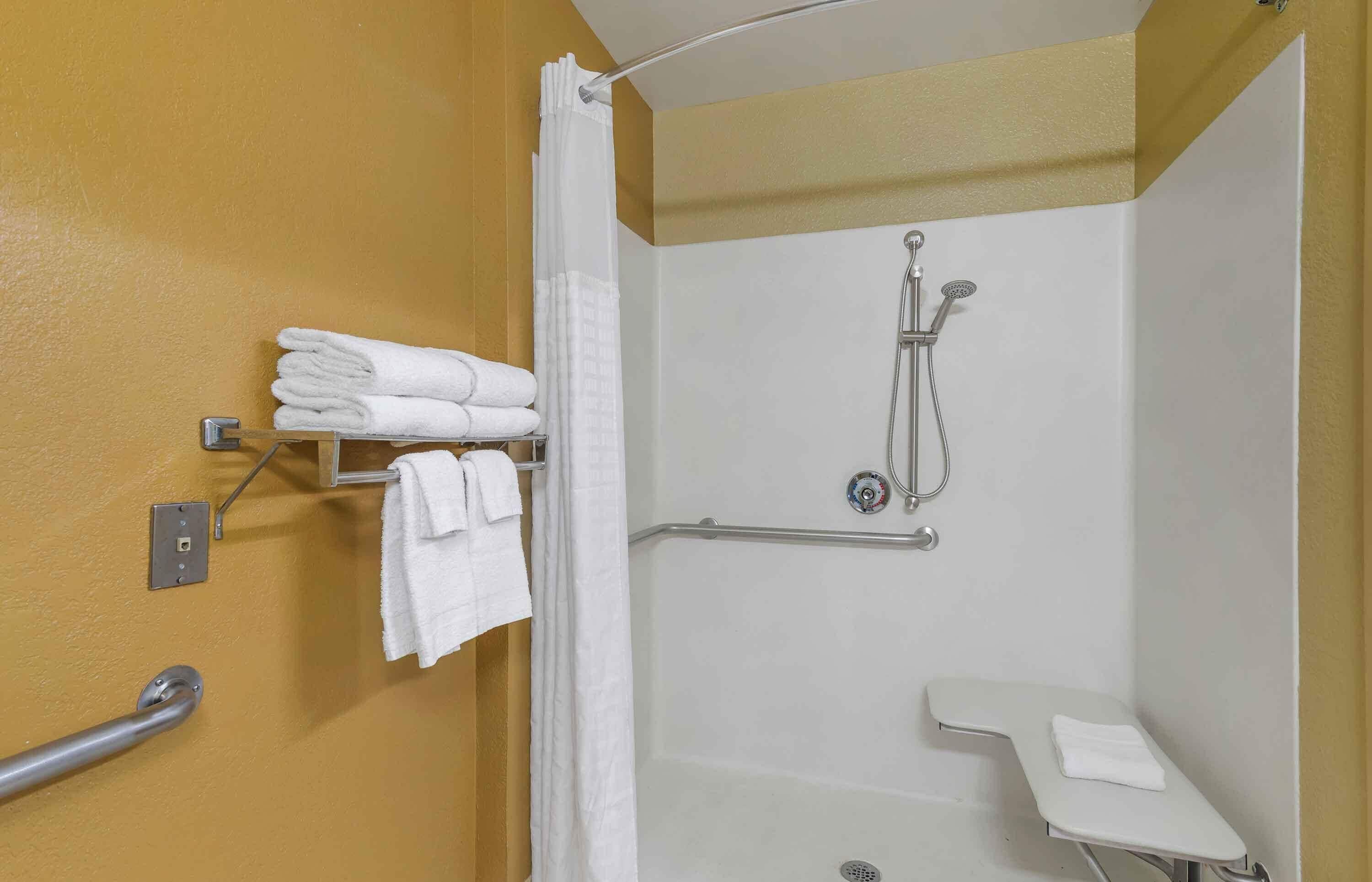 Une salle de bain équipée d’une douche, de toilettes et d’un porte-serviettes avec des serviettes pliées.