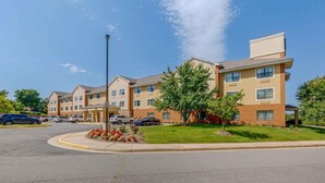A multi-story hotel with a central courtyard, parking lot, and a clear blue sky. - Extended Stay America Suites Washington DC Sterling (Sterling)