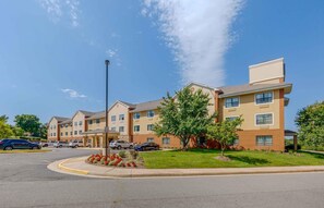 A multi-story hotel with a central courtyard, parking lot, and a clear blue sky. - Extended Stay America Suites Washington DC Sterling (Sterling)