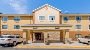 A hotel with a beige facade, a lobby entrance, and a parking lot with cars. - Extended Stay America Suites Washington DC Sterling (Sterling)