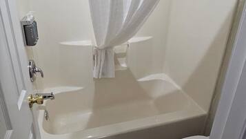 A bathroom with a bathtub, toilet, and shower curtain.