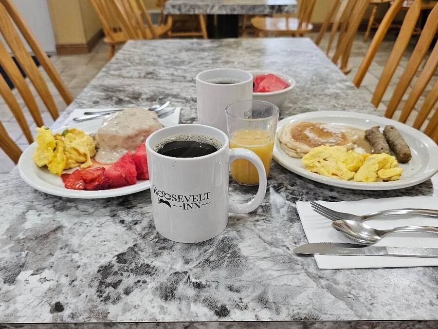 A breakfast table with plates of food, a coffee mug, and a juice glass.