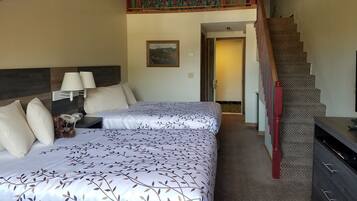 A bedroom with two beds, a staircase, and a hallway.