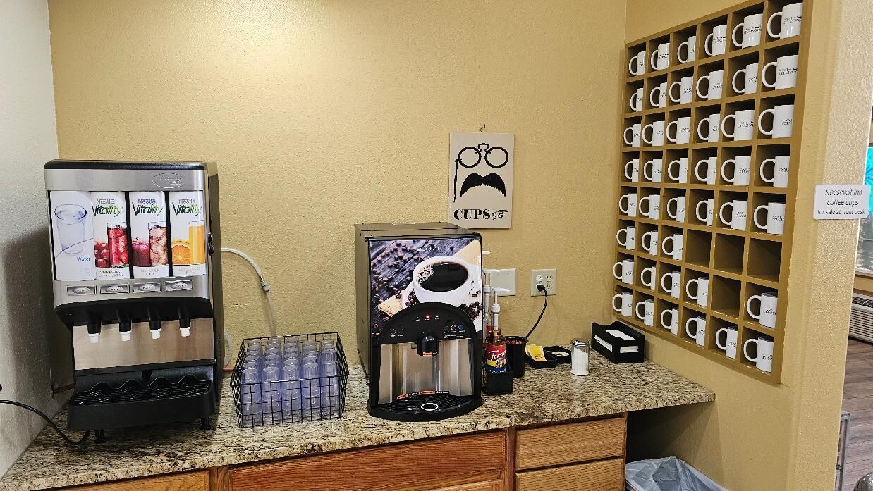 Eine Kaffeestation mit mehreren Kaffeemaschinen, einer Kaffeetassenpräsentation und einem wandmontierten Becherhalter.