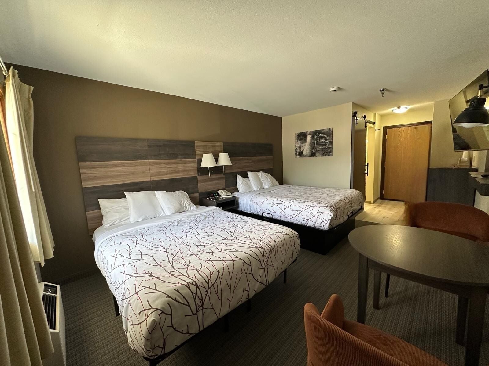 A hotel room with two beds, a dining table, and a chair.