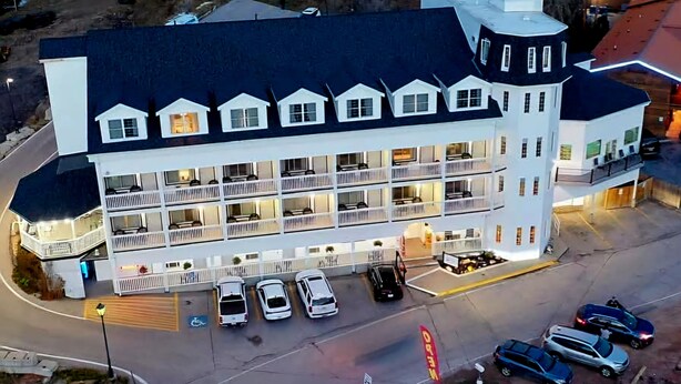 Un hotel de varios pisos con un patio central, múltiples balcones y un estacionamiento.