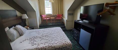 A hotel room with a bed, a TV, a desk, and a chair.