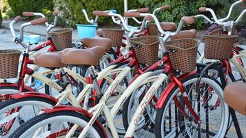Varias bicicletas con cestas y un contenedor azul al fondo.
