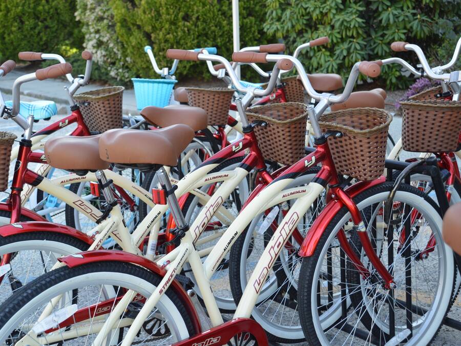 Varias bicicletas con cestas y un contenedor azul al fondo.