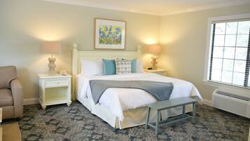 A bedroom with a bed, bedside tables, a bench, a chair, and a window.