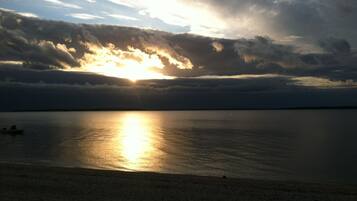 A sunset over a calm sea with a boat on the horizon.