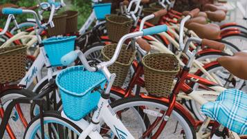 Une rangée de vélos équipés de paniers et de sacoches, garés très près les uns des autres.