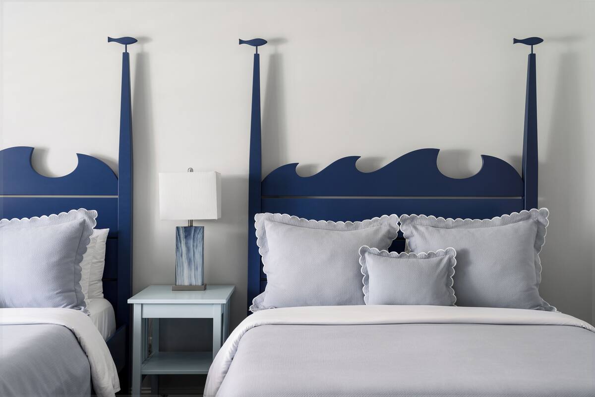 Un dormitorio con cama, dos mesitas de noche, una lámpara y estante en la pared.