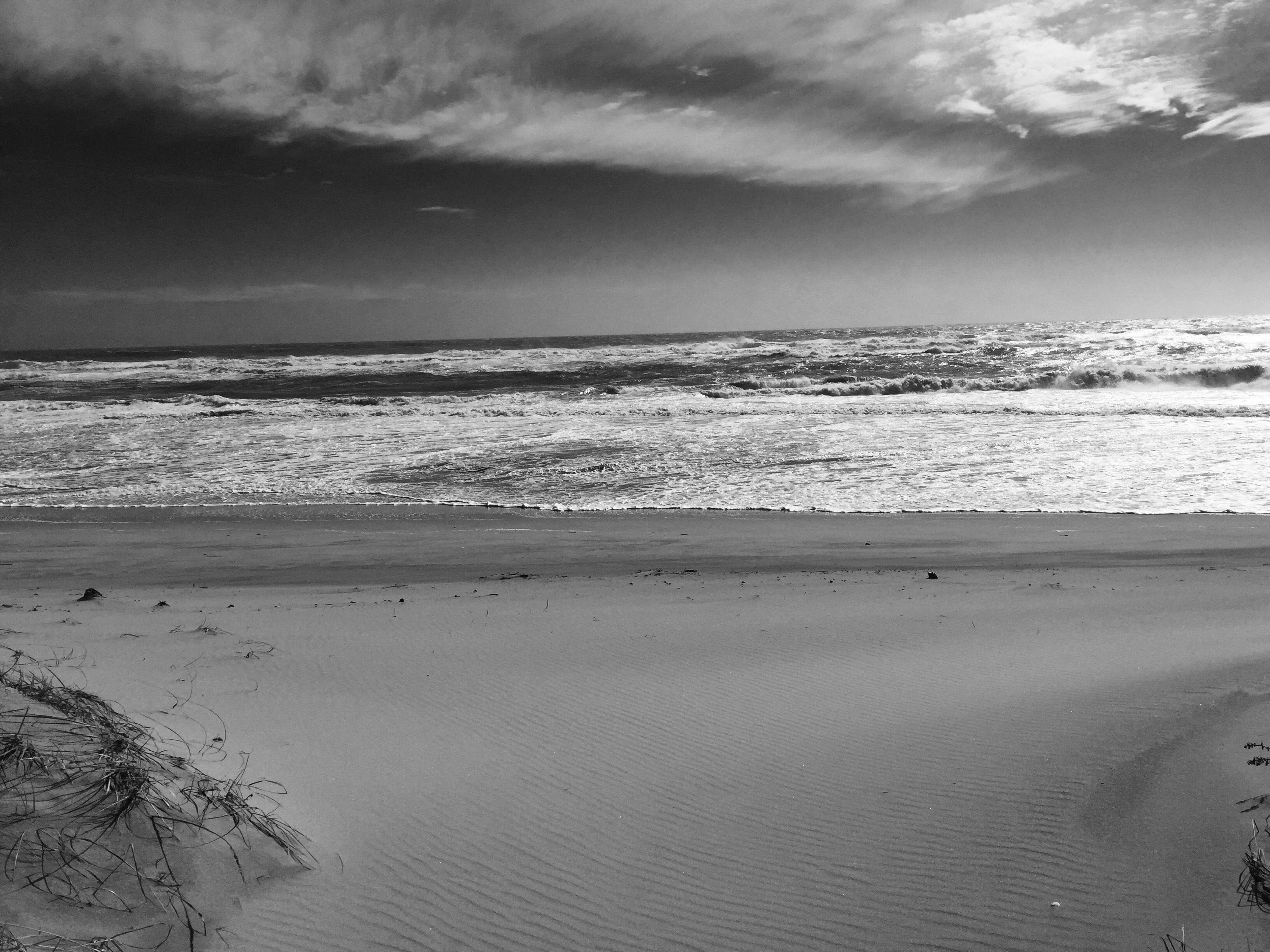 Una spiaggia con onde e un cielo nuvoloso.