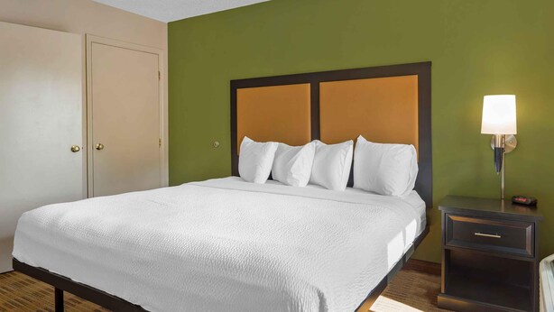Een hotelkamer met een bed, een nachtkastje met een lamp en een kledingkast.