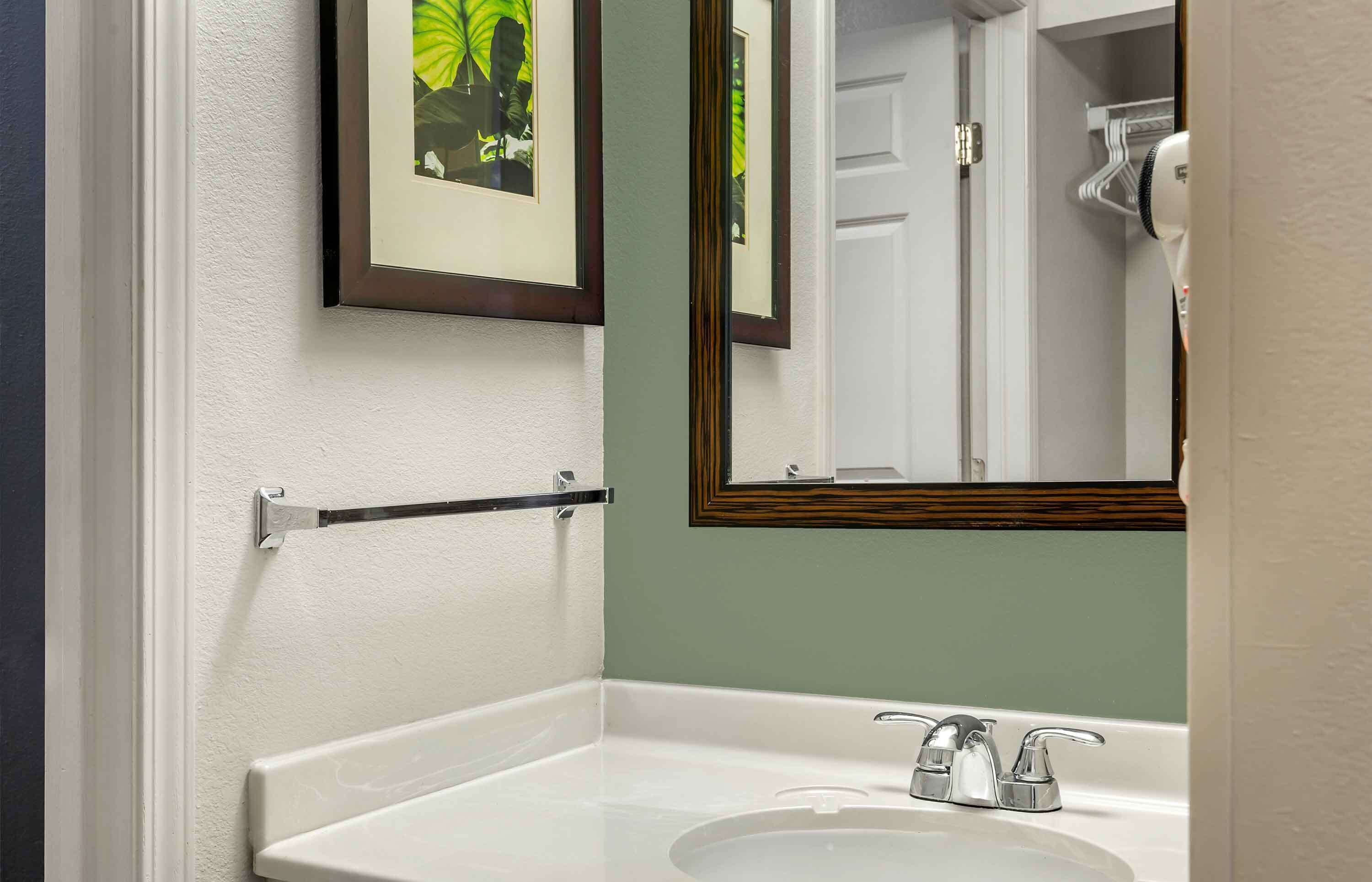 A bathroom with a white sink, a framed mirror, and a towel rack.