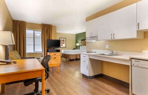 A compact hotel room with a kitchenette, a bed, a desk with a chair, a television, and a window with curtains. - Extended Stay America Suites Boston Westborough Computer Dr (Westborough)