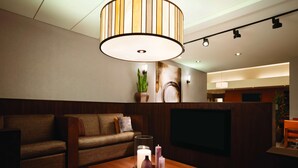 A modern living room with a sofa, a coffee table with candles, and a TV mounted on the wall. - HYATT house Pleasanton (Pleasanton)