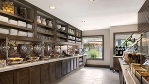 A modern kitchen with a long counter, various food containers, and shelves with dishes and utensils. - HYATT house Pleasanton (Pleasanton)