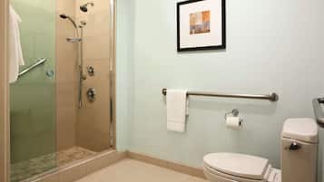 Un bagno con doccia vetrata, un water, un porta asciugamani e un quadro appeso al muro.