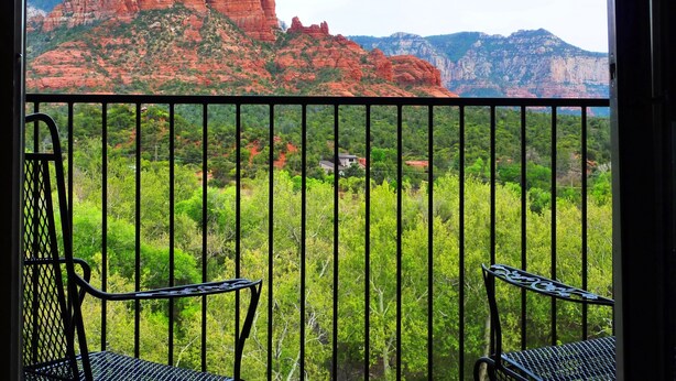 A balcony with two chairs, offering a view of red rock formations and green vegetation. - Cedars Resort (Sedona)