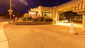 The entrance to Cedars Resort with a pedestrian crossing sign, a landscaped area with bushes, and a bridge overhead. - Cedars Resort (Sedona)