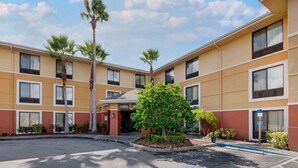 A multi-story hotel with a central lobby, palm trees, and a parking lot.