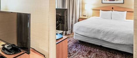 Habitación de hotel con cama, escritorio, televisor de pantalla plana, teléfono y lámpara.