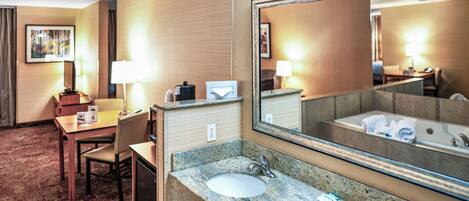 A hotel bathroom with a sink, mirror, and a bathtub.