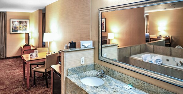 A hotel bathroom with a sink, mirror, and a bathtub.