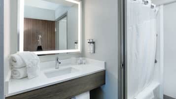 Un baño moderno con un espejo grande, dos lavamanos, una ducha y toallas ordenadas.