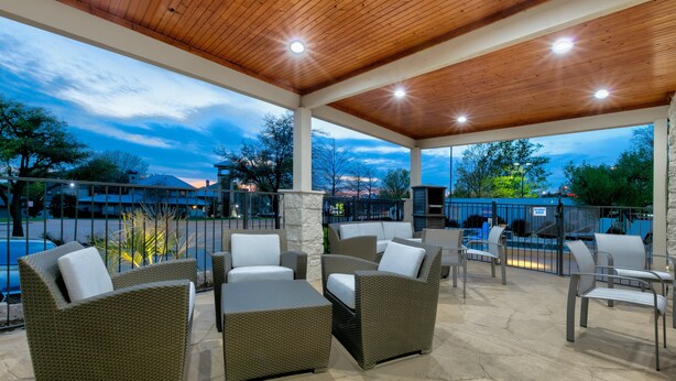 Ein Terrassenbereich im Freien mit Korbmöbeln und Steinboden, mit Blick auf einen Pool und eine Berglandschaft.