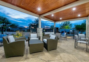 An outdoor patio area with wicker furniture and a stone floor, overlooking a pool and a mountainous landscape. - Holiday Inn Express & Suites Dallas Park Central Northeast by IHG (Dallas)
