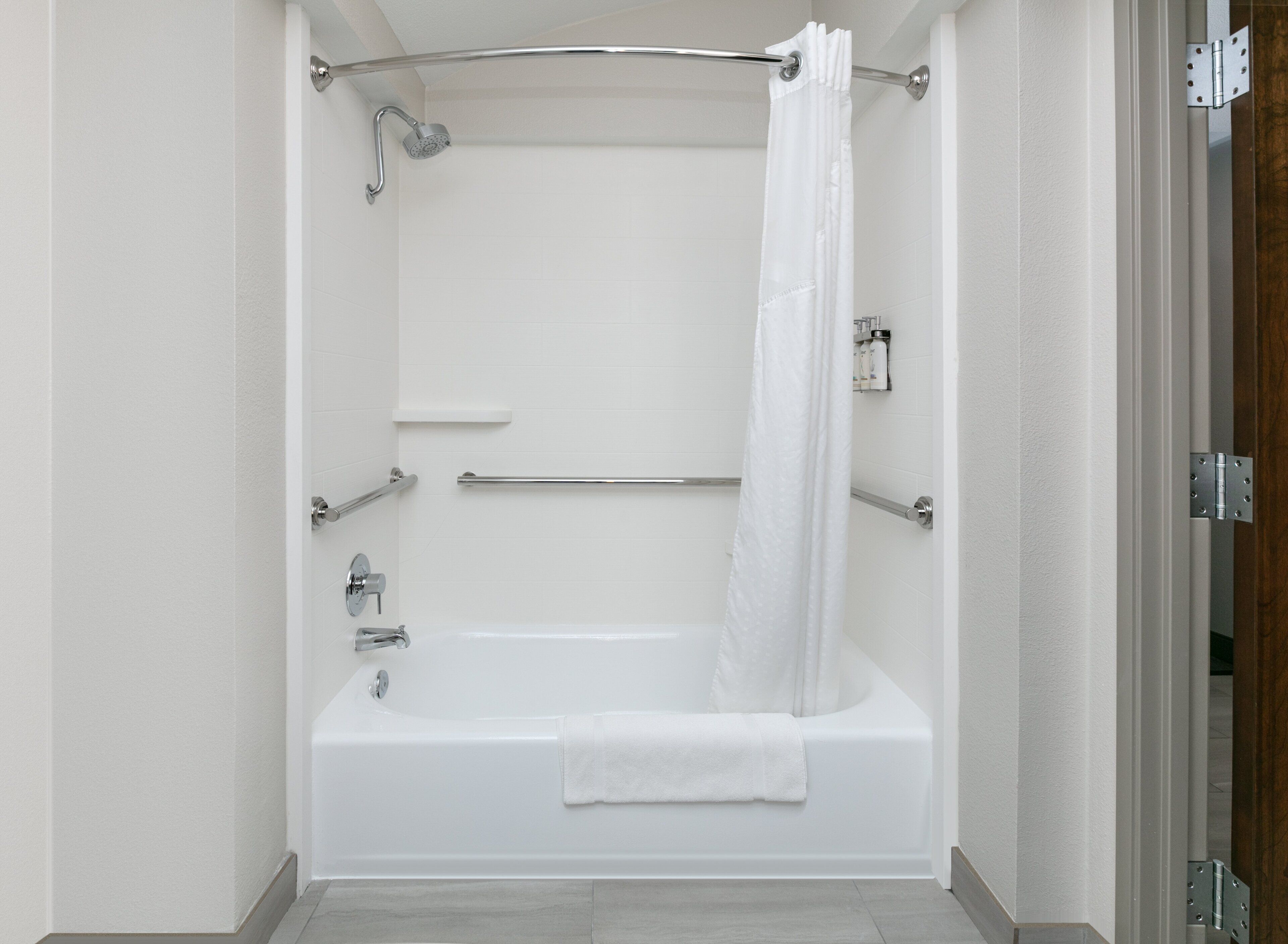 Un baño moderno con bañera, ducha y una cortina blanca.