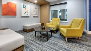 A modern lobby with a sofa, two yellow armchairs, a coffee table, and artwork on the walls. - Holiday Inn Express & Suites Dallas Park Central Northeast by IHG (Dallas)