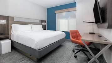 Una habitación de hotel con una cama, un escritorio, una silla, un televisor y una ventana.