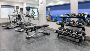 Ein Fitnessstudio mit Laufbändern, einer Bank und einer Hantelbank.