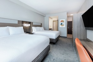 A hotel room with two beds, a flat-screen TV, a desk, and a bathroom visible through an open door. - Holiday Inn Express & Suites Dallas Park Central Northeast by IHG (Dallas)