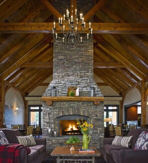 A cozy interior with a stone fireplace, wooden beams, and a chandelier. - Green Mountain Suites Hotel (South Burlington)