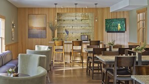 Un ristorante con pareti in legno, un'area bar e diverse disposizioni di posti a sedere, tra cui un divano e tavoli.
