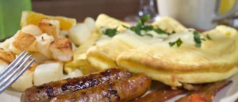 Un plato de desayuno con huevos, salchichas, tocino y papas.