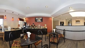 Un comedor de hotel con una isla central, sillas negras y una mesa de madera.